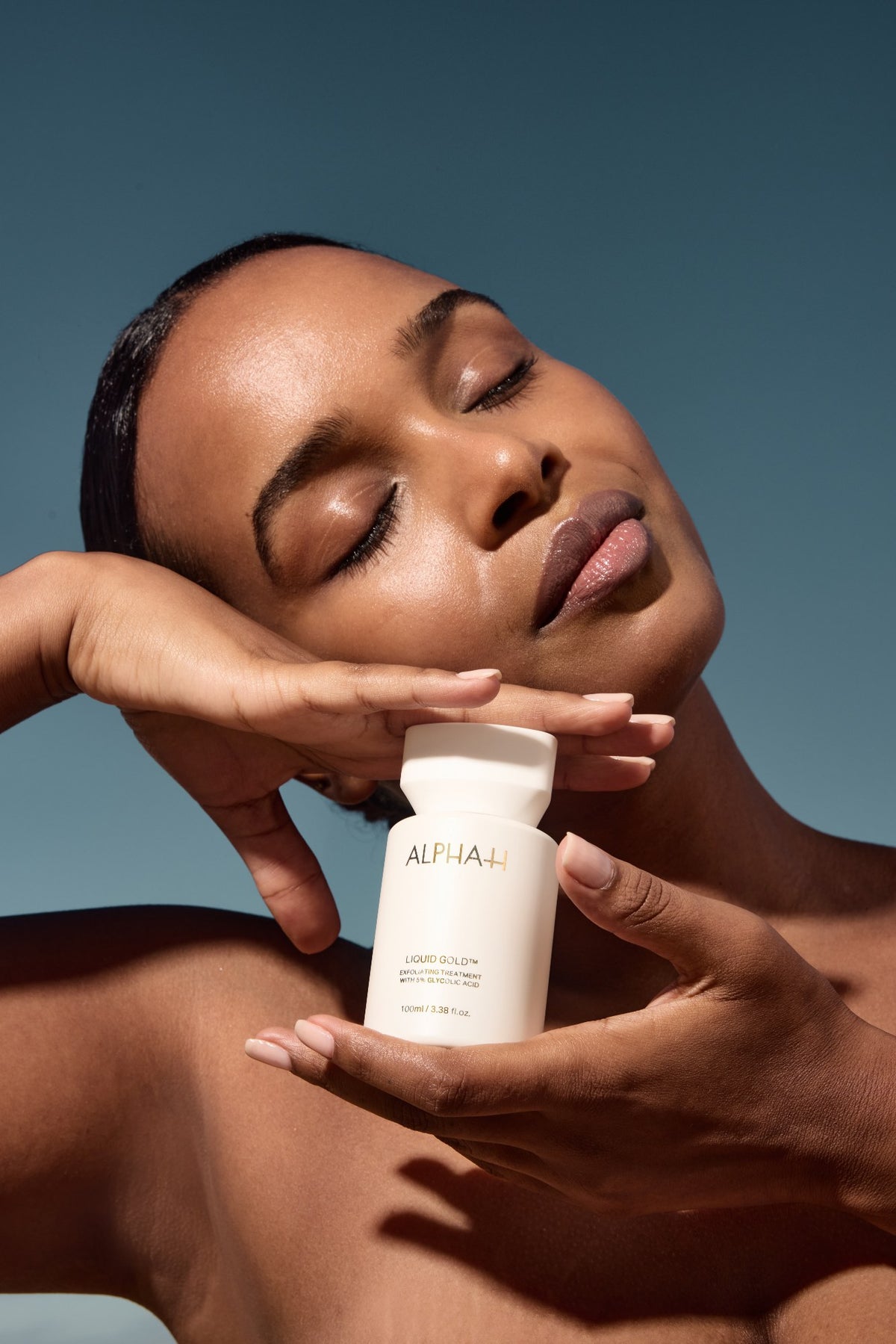Alpha-H Liquid Gold Exfoliating Treatment model met flacon in zonlicht
